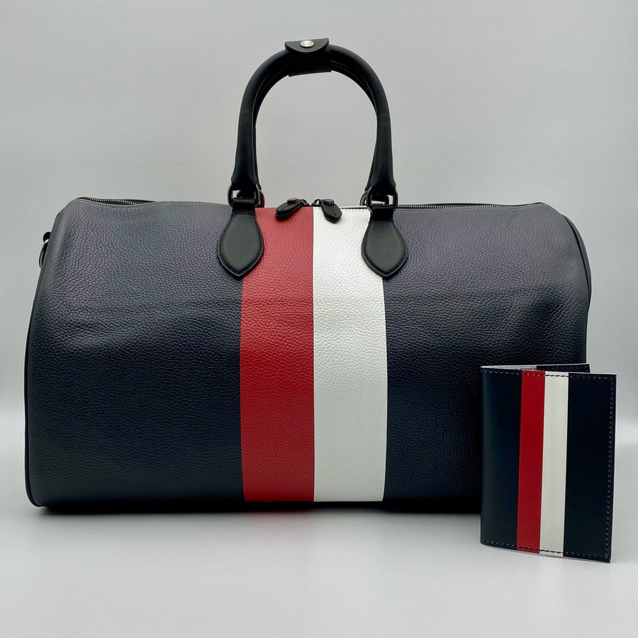 Matching black duffle bag and passport with red and white stripe on a white background