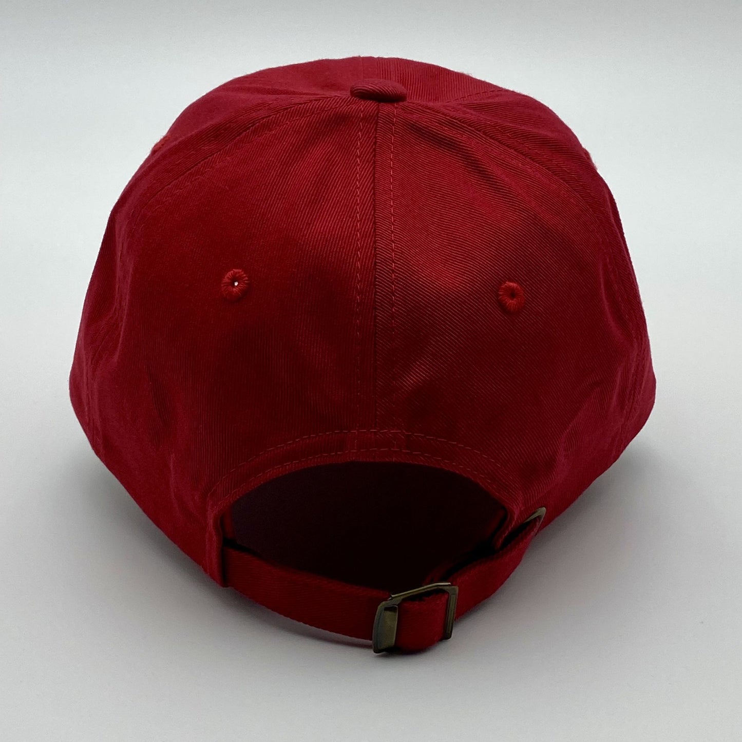 Back of a red racing hat with an adjustable strap on a white background