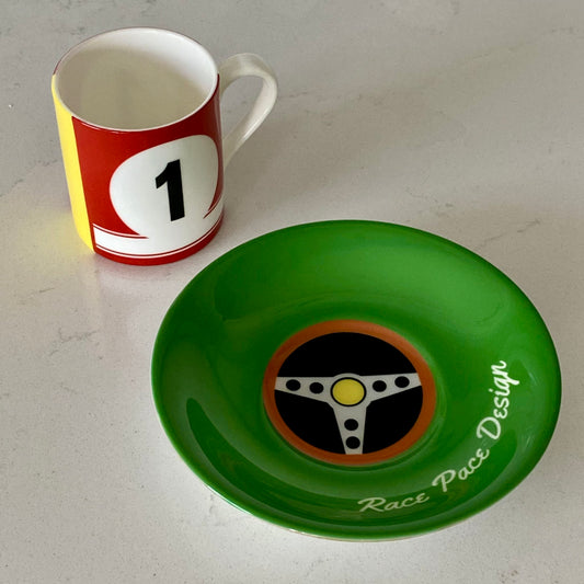 Cup with racing theme and green saucer with steering wheel design on a white surface