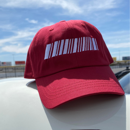 Red cap with a white barcode design on a car against a blue sky.