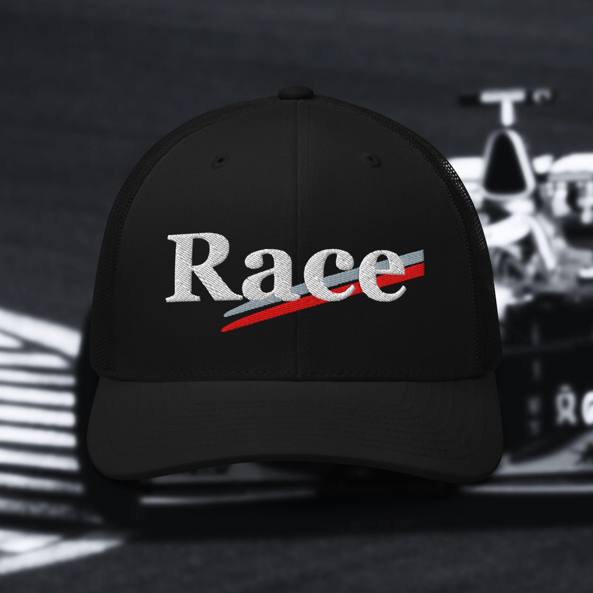 Black cap with 'Race' text in white with silver and red stripes on a blurred race car background
