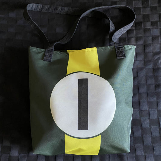 Green tote bag with a yellow racing stripe and number "1" in a white circle on a textured surface