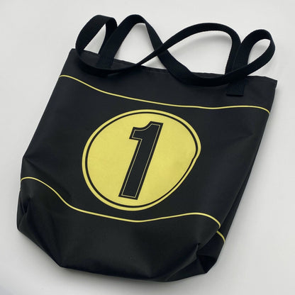 Black tote bag with gold stripes, circle and black number '1' on a light gray background