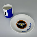 Racing cup and saucer set with steering wheel design on a gray background