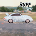 Dog toy shaped like a sports car with "Ruff Turbo" branding on a blurred race track background