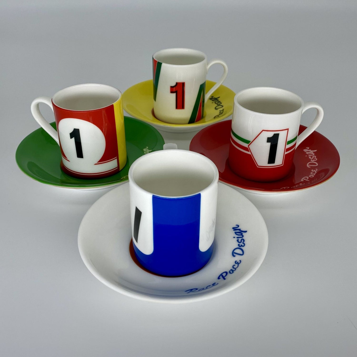 Set of four colorful coffee cups and saucers with number '1' design on a gray background